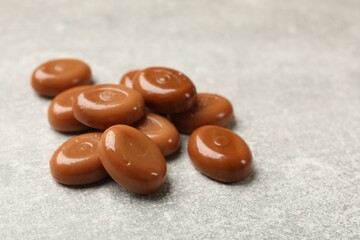 Many tasty caramel candies on grey table, closeup