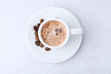 Aromatic coffee in cup, beans and saucer on light table, top view