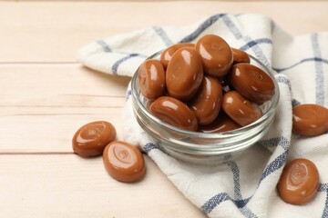 Many tasty caramel candies on white wooden table, closeup