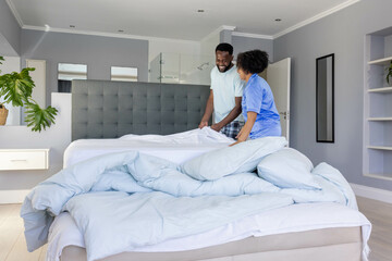 Young couple waking up in modern bedroom on large bed with white pillows and bedding