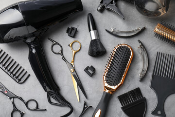 Different hairdresser's tools on grey table, flat lay