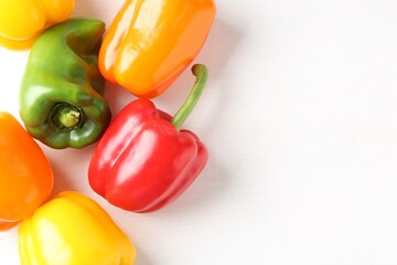 Ripe colorful bell peppers on white table, flat lay. Space for text