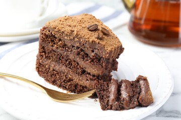 Piece of delicious chocolate cake with coffee beans and fork on white marble table, closeup