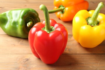 Ripe colorful bell peppers on wooden table, closeup
