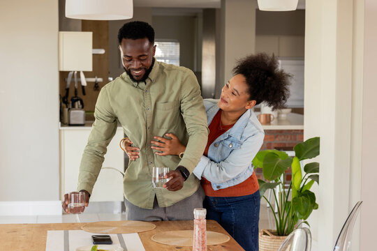 Happy couple enjoying quality time together at home, holding glasses and smiling