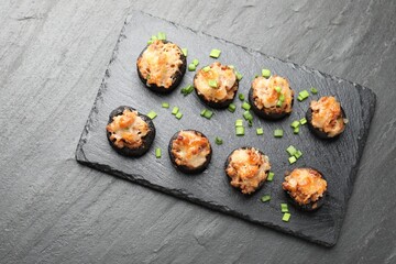 Tasty stuffed mushrooms served on black table, top view
