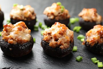 Tasty stuffed mushrooms served on black table, closeup