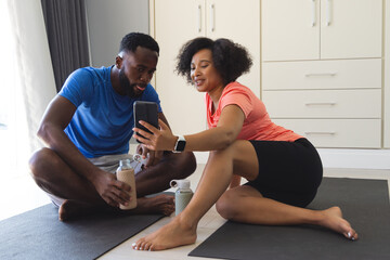 Couple on yoga mats watching video on smartphone, enjoying fitness routine together