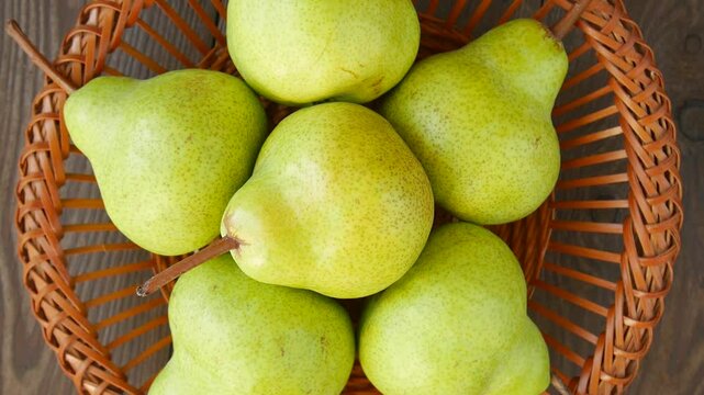 Green pears gently rotating in wicker basket, showcasing fresh agricultural produce with rustic stop-motion animation style on wooden surface.