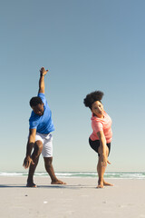 Fototapeta premium African American couple practicing yoga on beach, enjoying sunny day together