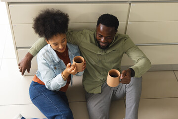 Couple sitting on kitchen floor enjoying coffee, sharing joyful moment together