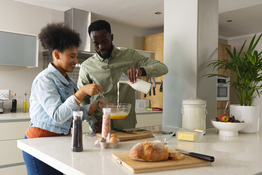 Couple cooking together in modern kitchen, mixing ingredients and enjoying time