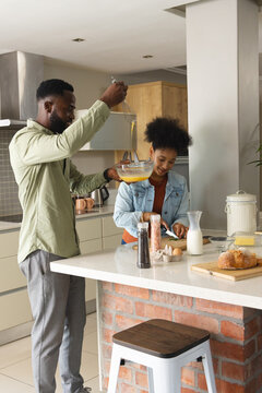 Couple cooking breakfast together in modern kitchen, whisking eggs and smiling