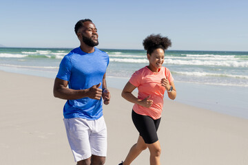 Fototapeta premium Couple jogging on beach, enjoying sunny day and staying active together