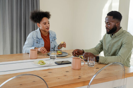 Couple enjoying breakfast together at home, sharing avocado toast and coffee