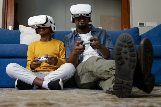 African American African American father and son playing video games with VR headsets at home