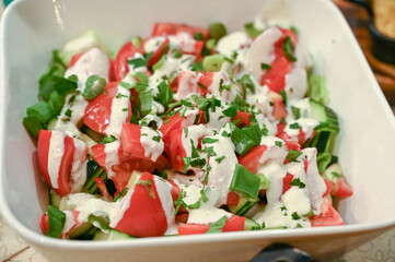 Vegetable salad. Fresh salad on a plate in a restaurant. Tomato, spring onion, parsley and sauce.
