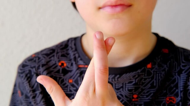 child's crossed fingers for luck, 11-year-old boy making motivational Symbolism and Gestures of Believing in Luck symbolizing hope, support, optimism concept emotional development