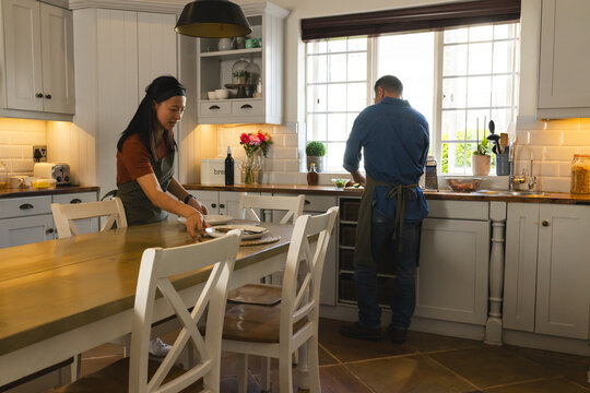Mature Asian couple preparing meal together in cozy kitchen, enjoying quality time