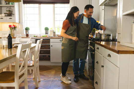 Asian couple cooking together in kitchen, enjoying time and preparing meal