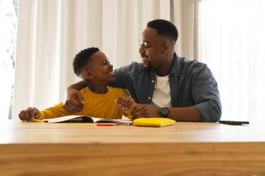 African American father and son smiling and bonding over homework at home