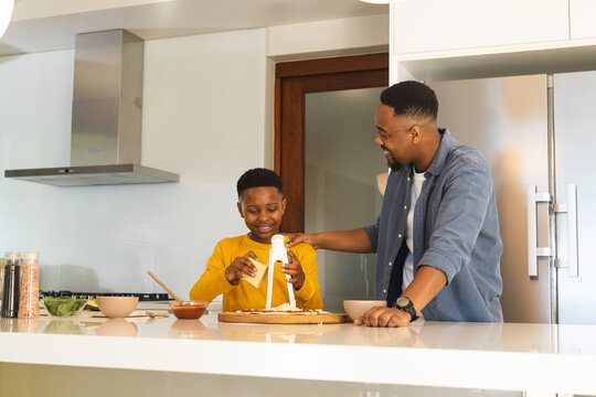 African American father and son cooking together in modern kitchen, enjoying time