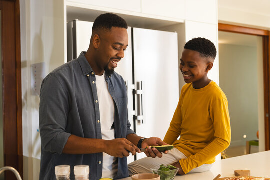 Father and son preparing meal together in kitchen, sharing joyful moment