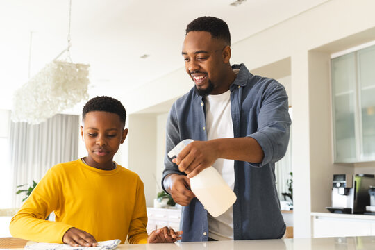 Father and son cleaning kitchen together, bonding and enjoying household chores