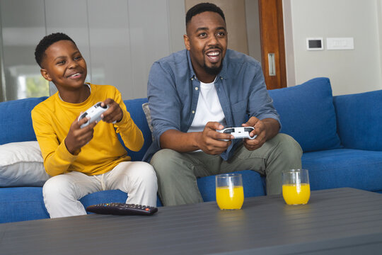 Father and son playing video games on couch, enjoying quality time together