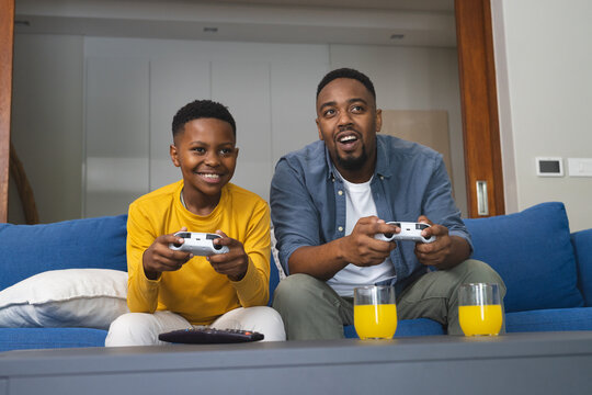 Father and son playing video games on couch, enjoying quality time together