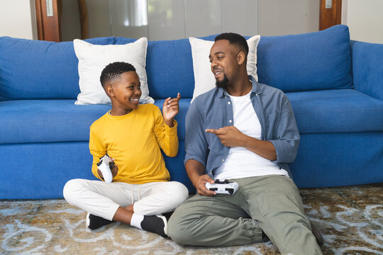 Father and son playing video games on living room floor, sharing joyful moment
