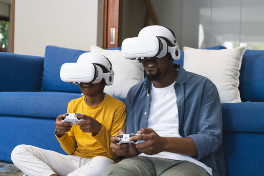 African American father and child gaming on patterned rug with VR controllers in cozy living room