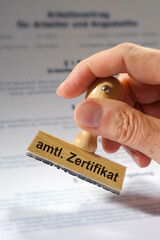 Ein Holzstempel ist beschriftet mit dem Aufdruck Bestätigung