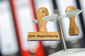 Ein Holzstempel ist beschriftet mit dem Aufdruck amtliche Beglaubigung