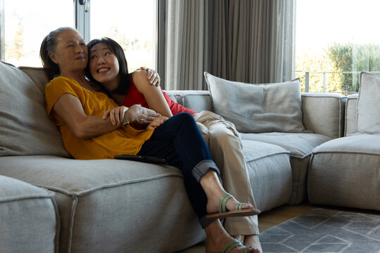 Asian senior mother and daughter relaxing on sofa at home, enjoying quality time together