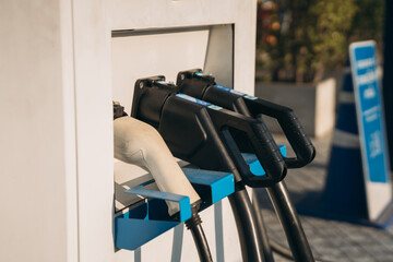 Close-up of a hand plugging an electric vehicle charger into a charging station, clean energy and eco-friendly transportation concept.