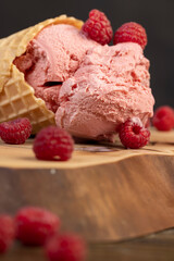 ripe red raspberries and raspberry cold natural ice cream on the table, close up, side view
