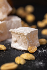 Turkish delight with peanut on a black slate board, sweets made from sugar and molasses, closeup