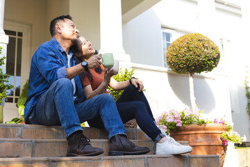 Mature couple relaxing on porch steps, enjoying coffee and peaceful morning together
