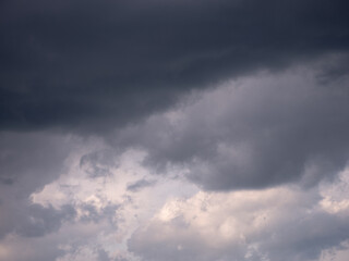 Layered dark and light clouds in the sky, showing a contrast between shadow and soft light. A natural weather scene symbolizing tension and calm, often tied to spiritual reflection.