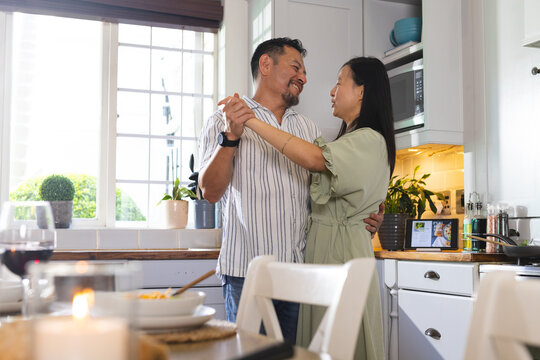 Mature couple dancing happily in kitchen, enjoying quality time together at home