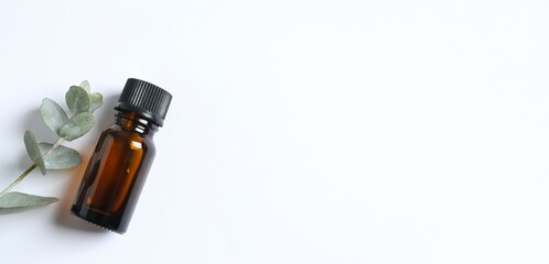 Eucalyptus essential oil in a glass bottle with green eucalyptus leaves on a white background. Aromatherapy concept. Spa. Natural organic ingredients for cosmetics and body care. Top view