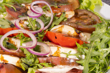 Fresh vegetable salad with mozzarella cheese and vinaigrette dressing, close up