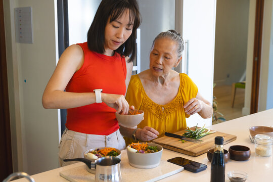 Cooking Asian Chinese family preparing vegetable salad at kitchen island, with ceramic bowls