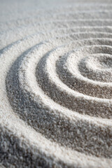Obraz premium Close-up of concentric rake patterns in white sand from a Japanese zen garden, perfectly symmetrical and calming, ideal for meditation and minimalist decor.