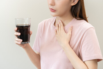 Acid reflux disease, suffer asian young woman, girl hand holding a glass of cola, have symptom...