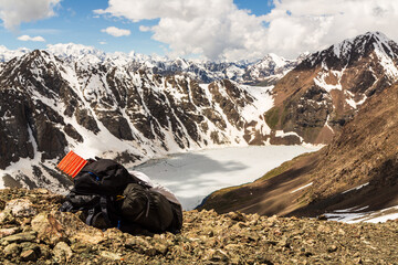 Backpack on the mountain pass with a view over the frozen lake Ala-Kul from mountain pass. Tien Shan. Kyrgyzstan