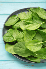 Fresh spinach leaves on blue wooden background. Vertical photo