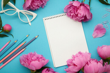 Beautiful pink peony flowers with empty notebook on blue background, copy space for your text or design. To do list