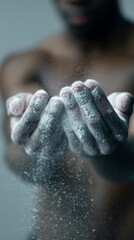 dark-skinned gymnast claps his chalk-covered hands together in a bright, all-white gym